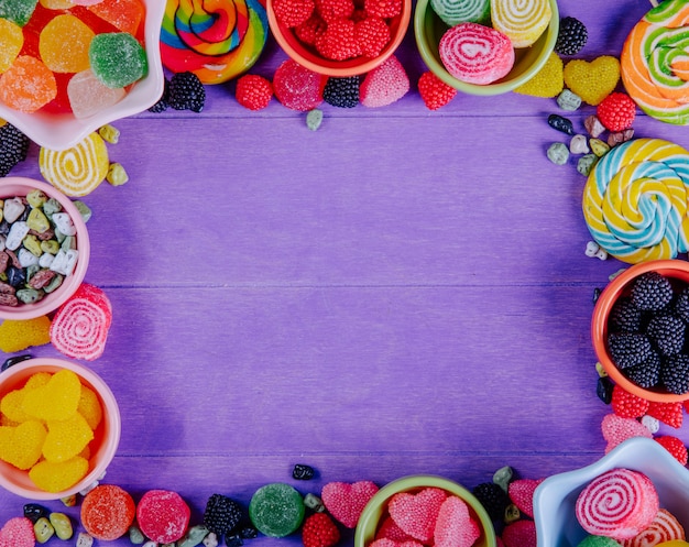 Vista superior copia espacio mermelada multicolor con piedras de chocolate y carámbanos de colores en platillos para mermelada sobre un fondo morado