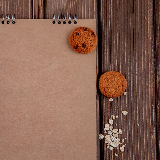 Vista superior copia espacio portátil con galletas y avena sobre un fondo de madera