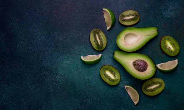 Foto gratuita vista superior copia espacio rodajas de kiwi mitades de aguacate y rodajas de limón sobre un fondo verde oscuro