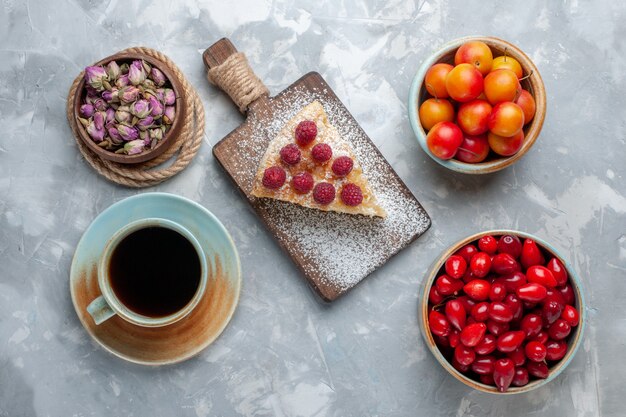 Vista superior de cornejos frescos rojos frutas agrias y deliciosas con pastel y té en la mesa de luz fruta fresca agria suave