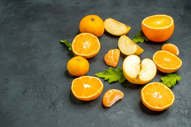 Vista superior cortadas naranjas y manzanas sobre fondo oscuro