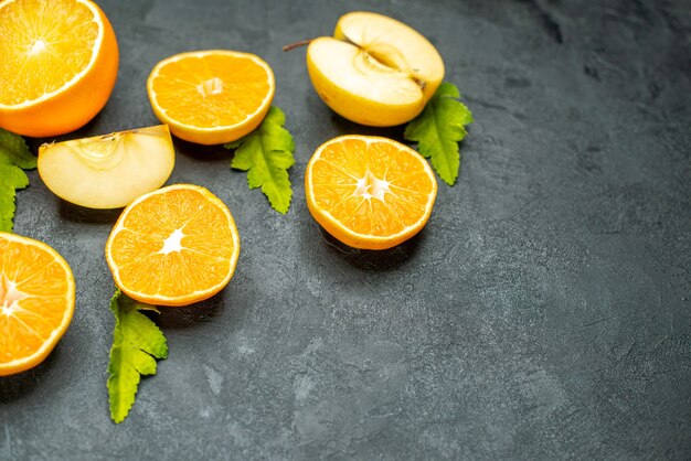 Vista superior cortadas naranjas y manzanas en superficie oscura