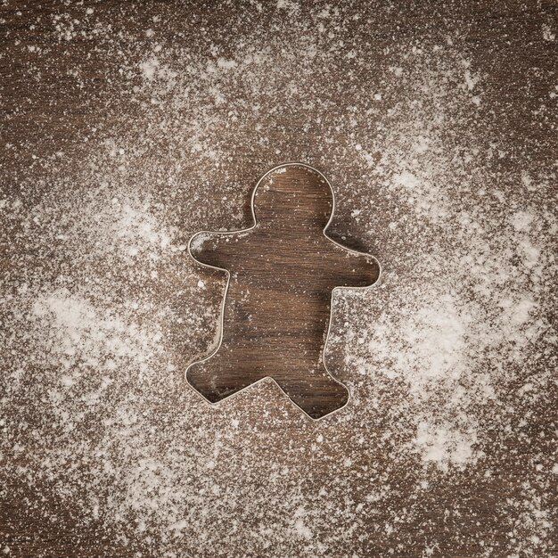 Vista superior cortador de galletas de hombre de jengibre con harina