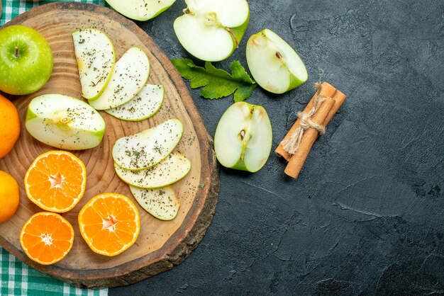 Vista superior cortar manzanas y mandarinas con polvo de menta seca sobre tablero de madera