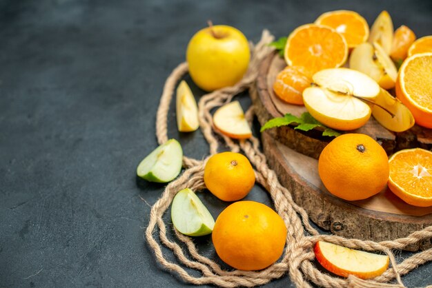 Vista superior cortar manzanas y naranjas en cóctel de tablero de madera sobre fondo oscuro