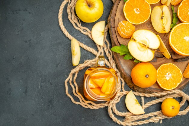 Vista superior cortar manzanas y naranjas en cóctel de tablero de madera sobre fondo oscuro