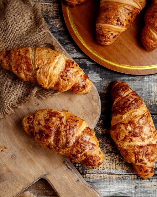 Vista superior de croissants de mantequilla colocados sobre tabla de madera