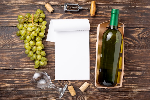 Foto gratuita vista superior del cuaderno al lado de la botella de vino