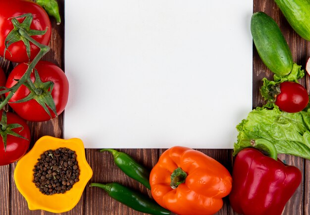 Vista superior del cuaderno de bocetos y verduras frescas pimientos coloridos chiles verdes tomates y granos de pimienta negra en la mesa de madera rústica