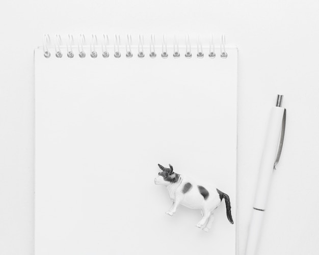 Vista superior del cuaderno con bolígrafo y figura de animal para el día de los animales