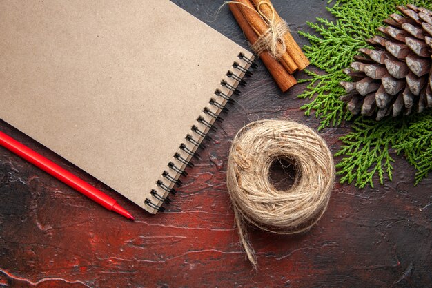 Vista superior del cuaderno cerrado con lápiz canela limas una bola de cuerda sobre fondo oscuro