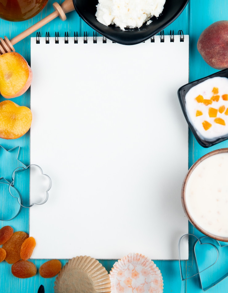 Foto gratuito vista superior de un cuaderno de dibujo y duraznos maduros frescos albaricoques secos yogur de requesón y cortadores de galletas dispuestos en azul