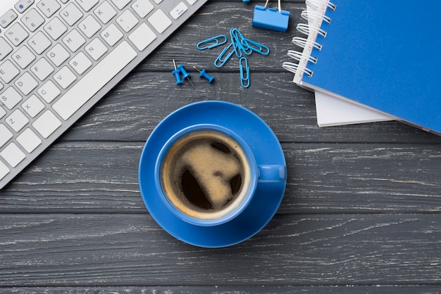 Vista superior del cuaderno en el escritorio de madera con taza de café y clips de papel