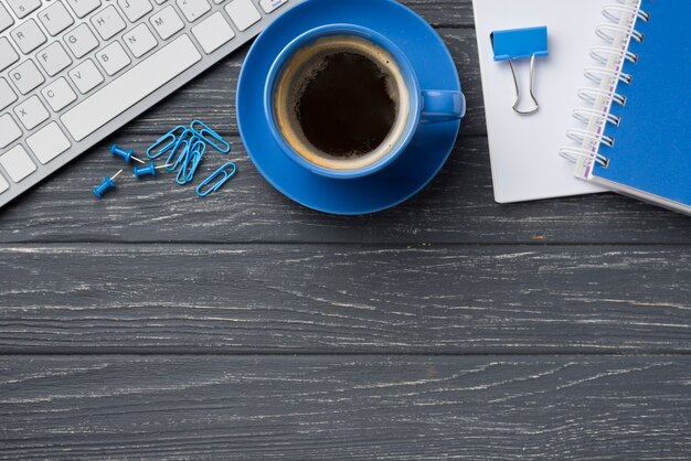 Vista superior del cuaderno en el escritorio de madera con taza de café y teclado