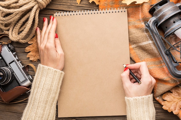 Vista superior del cuaderno con hojas de otoño y cámara