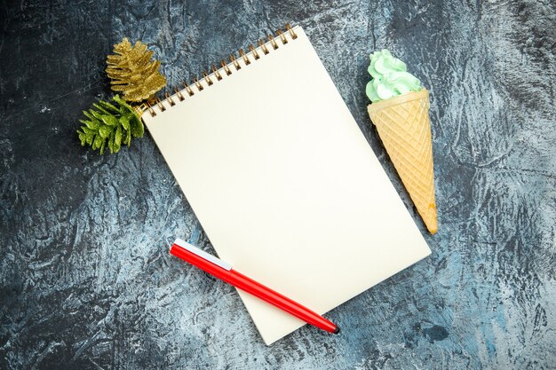 Vista superior de un cuaderno de Navidad detalles helado de bolígrafo rojo sobre fondo oscuro