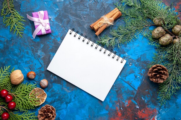 Vista superior cuaderno ramas de abeto conos juguetes de árbol de navidad sobre fondo azul lugar libre