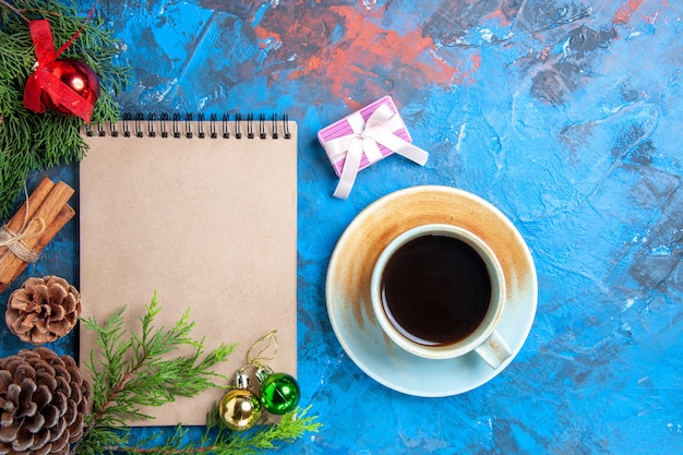 Foto gratuita vista superior de un cuaderno ramas de pino piña una taza de té sobre fondo azul espacio libre