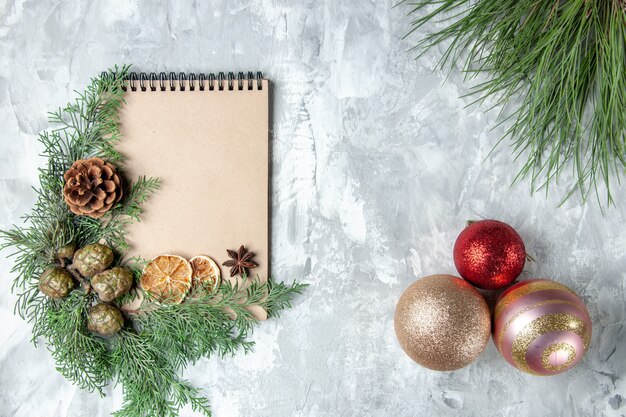 Vista superior del cuaderno seco rodajas de limón anís ramas de los árboles de pino juguetes del árbol de navidad en la superficie gris