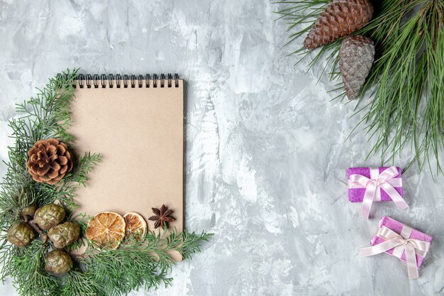 Vista superior cuaderno seco rodajas de limón anís ramas de pino pequeños regalos sobre superficie gris