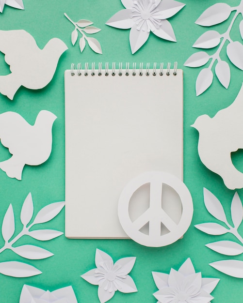Foto gratuita vista superior del cuaderno con signo de la paz y palomas de papel