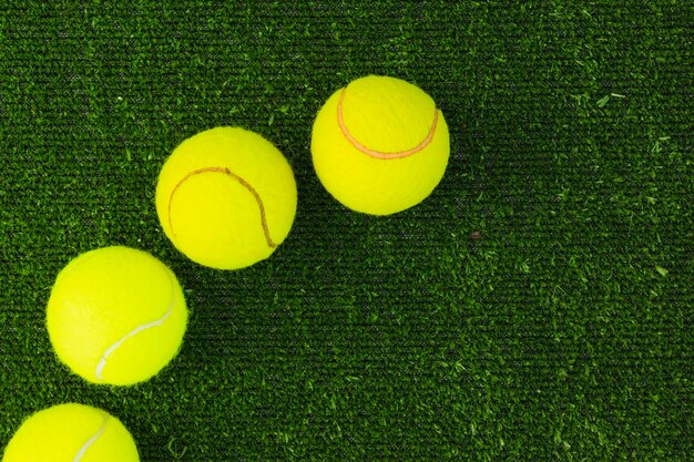 Vista superior de cuatro bolas de raqueta en césped verde
