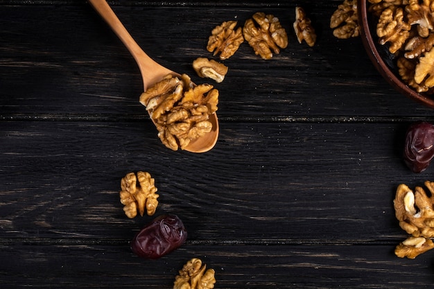 Foto gratuita vista superior de una cuchara de madera con nueces y frutas dulces de dátiles secos en madera
