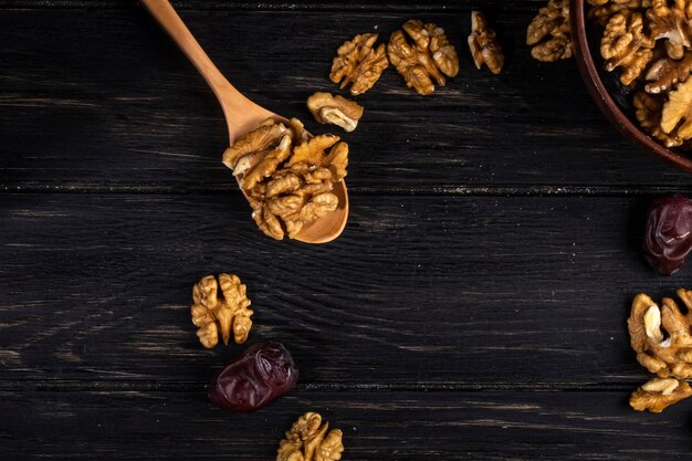 Vista superior de una cuchara de madera con nueces y frutas dulces de dátiles secos en madera