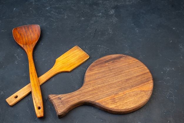 Foto gratuita vista superior de cucharas de madera de tablero redondo de madera en el espacio de copia de mesa oscura