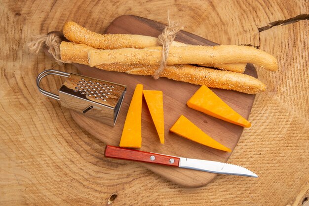 Vista superior del cuchillo de pan y queso rallador pequeño en la tabla de cortar