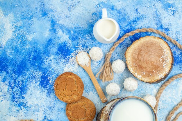 Vista superior cuencos de leche tableros de madera bolas de coco coco en polvo en cucharas de madera cuerda galletas sobre fondo blanco azul