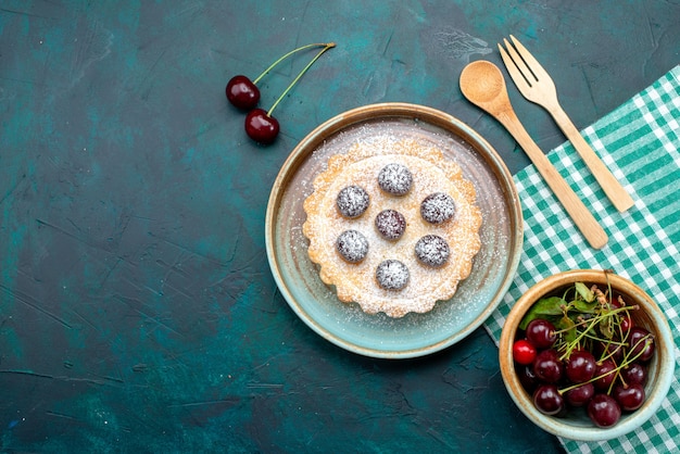 Vista superior de cupcake con deliciosas cerezas y azúcar en polvo junto a la placa de cereza