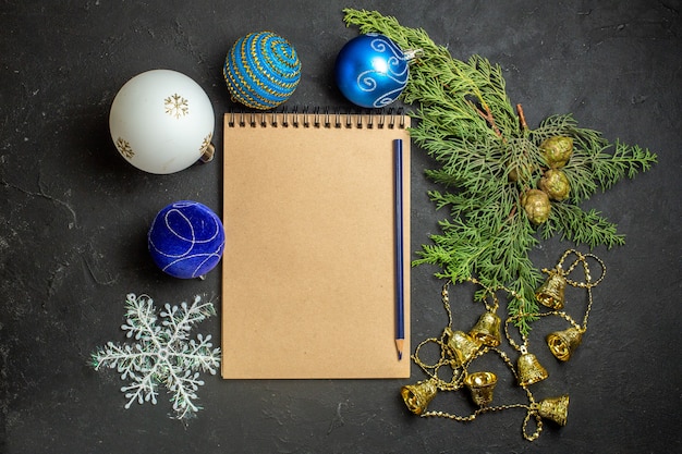 Vista superior de las decoraciones de año nuevo y cuaderno con bolígrafo sobre fondo negro