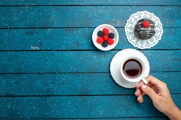 Vista superior deliciosa bola de chocolate con taza de té en el escritorio rústico azul pastel de té galleta galleta dulce
