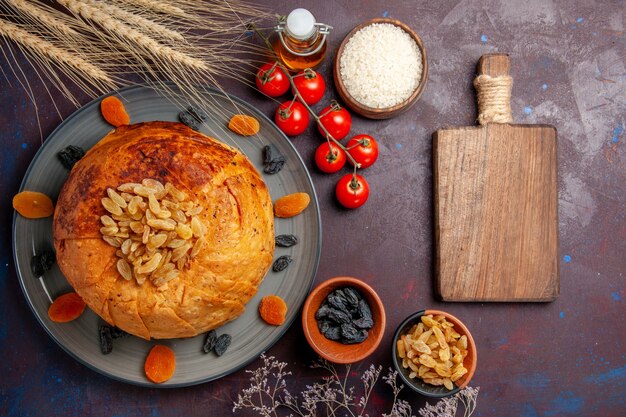 Vista superior deliciosa comida de arroz cocido de shakh plov con pasas y tomates en el fondo oscuro masa de comida cocinando cena de arroz