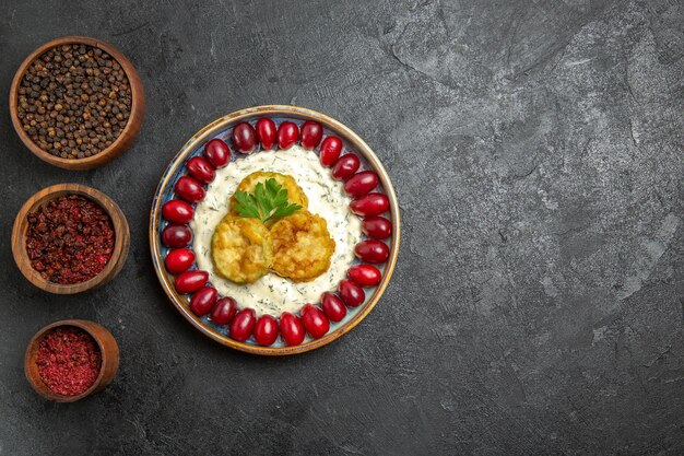 Vista superior de la deliciosa comida de calabaza con cornejos rojos frescos y condimentos sobre una superficie gris