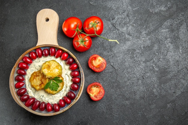 Vista superior de la deliciosa comida de calabaza con cornejos rojos frescos y tomates en superficie gris