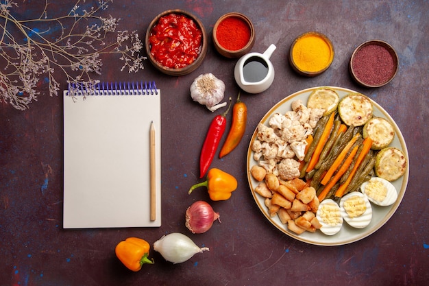 Vista superior deliciosa comida de huevo con verduras cocidas y condimentos en el espacio oscuro