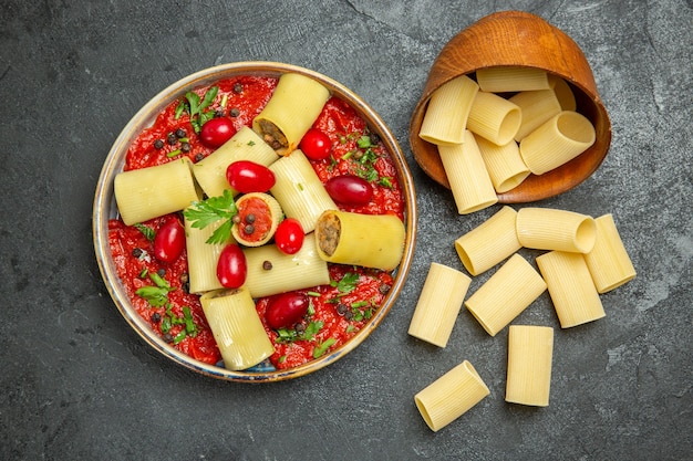 Vista superior de la deliciosa comida de pasta italiana cocida con salsa de tomate en la superficie gris pasta de salsa de comida de carne de masa