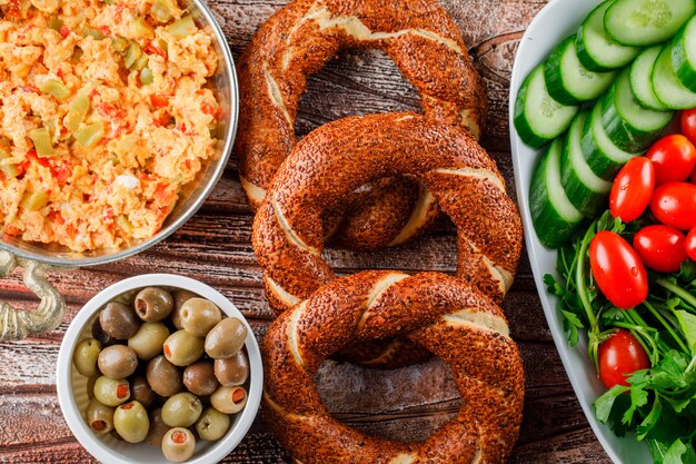 Vista superior deliciosa comida en plato con bagel turco, ensalada, encurtidos en un tazón sobre superficie de madera