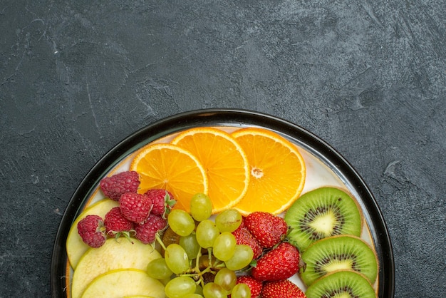 Foto gratuita vista superior de la deliciosa composición de frutas frescas en rodajas y frutas suaves en el piso oscuro, madura, fresca, suave dieta de salud