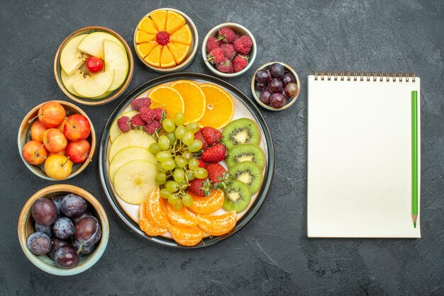 Vista superior de la deliciosa composición de frutas frutas frescas y en rodajas sobre fondo oscuro frutas maduras y frescas de la dieta de la salud suave