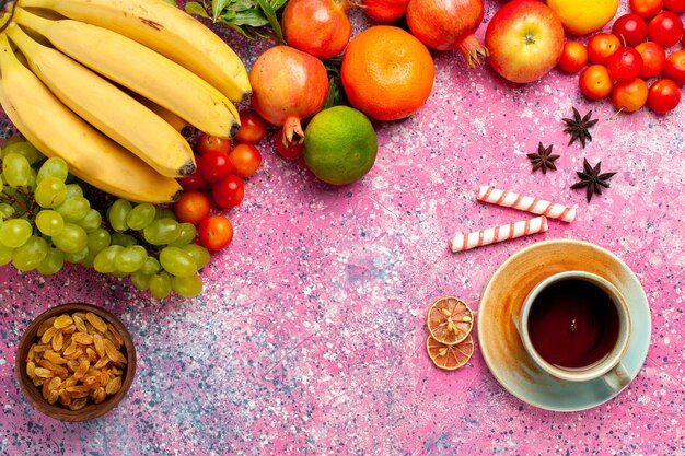 Vista superior de la deliciosa composición de frutas con té en el escritorio rosa