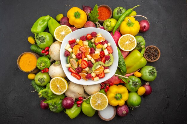 Vista superior deliciosa ensalada de frutas dentro de la placa con frutas frescas en el árbol de fruta gris exótica foto tropical dieta madura