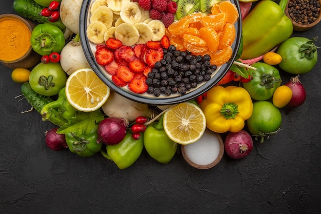 Vista superior deliciosa ensalada de frutas dentro del plato con frutas frescas en fotos de dieta madura exótica de árbol de frutas tropicales grises