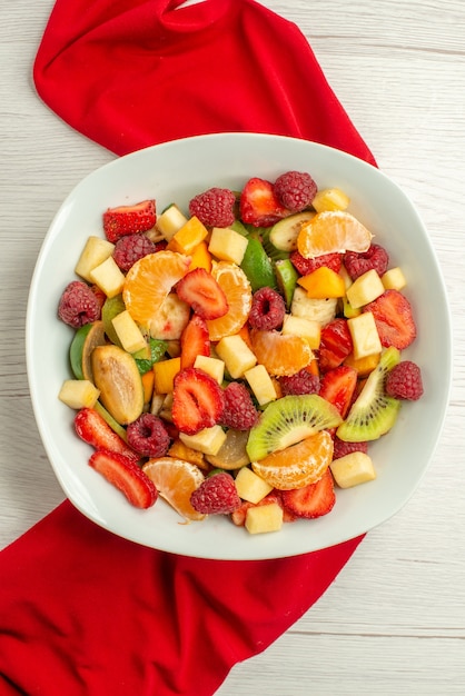 Foto gratuita vista superior deliciosa ensalada de frutas con tejido rojo sobre cítricos blancos baya frutal exótica madura suave