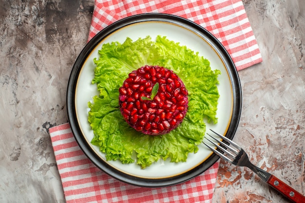 Vista superior deliciosa ensalada de granada en forma redonda en ensalada verde sobre fondo claro