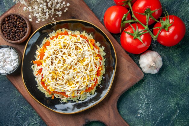 Vista superior deliciosa ensalada de mimosa dentro de la placa con tomates rojos sobre fondo azul oscuro