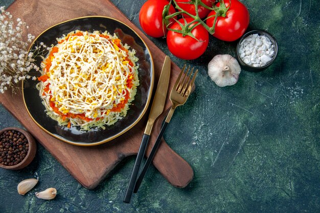 Vista superior deliciosa ensalada de mimosa dentro de la placa con tomates rojos sobre fondo azul oscuro