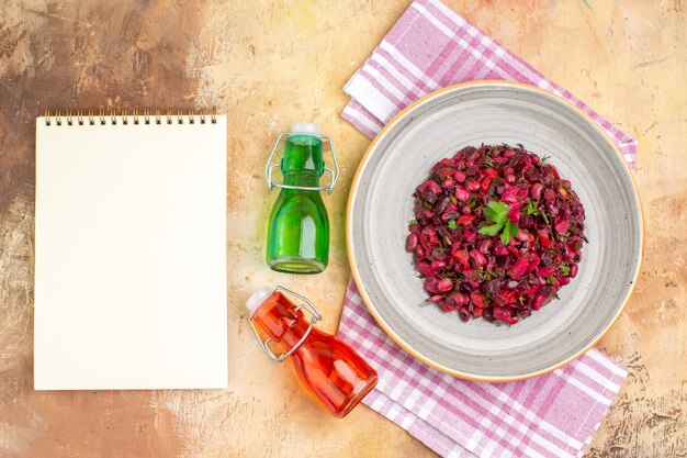 Vista superior deliciosa ensalada orgánica con excelentes botellas de aceite rojo y verde y libro de recetas